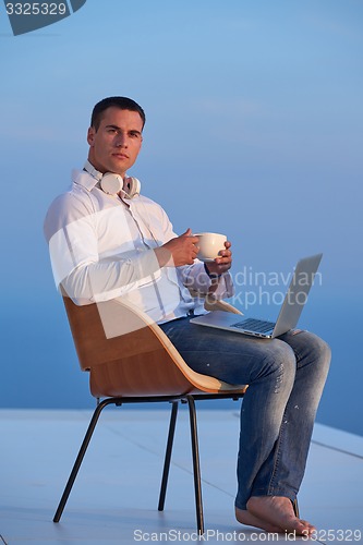 Image of relaxed young man at home on balcony