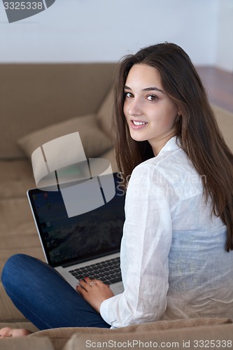 Image of relaxed young woman at home working on laptop computer