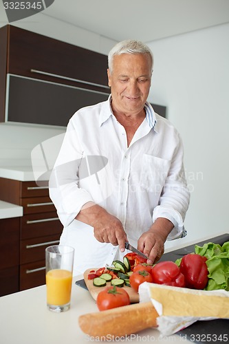 Image of man cooking at home preparing salad in kitchen