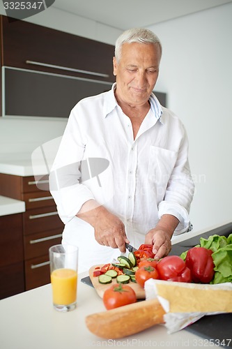 Image of man cooking at home preparing salad in kitchen