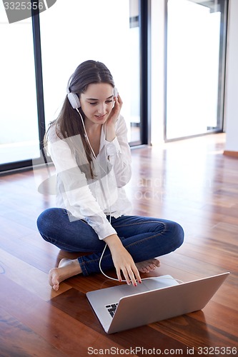 Image of relaxed young woman at home working on laptop computer