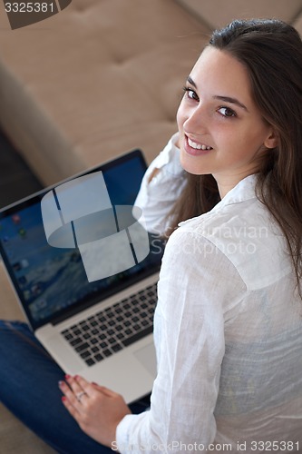 Image of relaxed young woman at home working on laptop computer