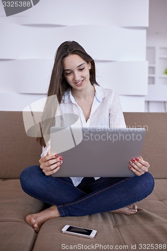 Image of relaxed young woman at home working on laptop computer