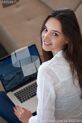 Image of relaxed young woman at home working on laptop computer