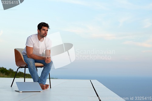 Image of relaxed young man at home on balcony