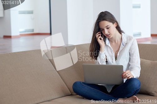 Image of relaxed young woman at home working on laptop computer