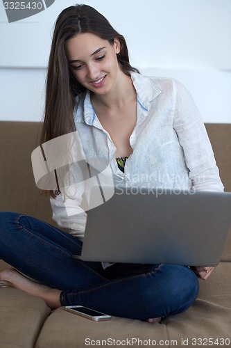 Image of relaxed young woman at home working on laptop computer