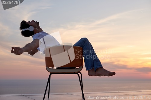 Image of relaxed young man at home on balcony