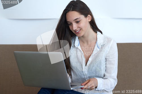Image of relaxed young woman at home working on laptop computer