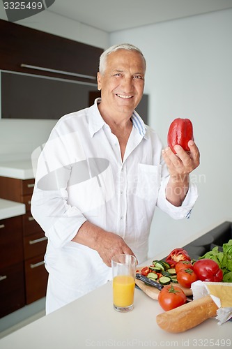 Image of man cooking at home preparing salad in kitchen