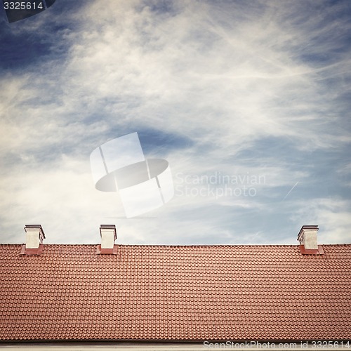 Image of cloudy blue sky and tiled roof top