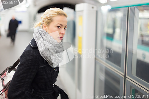 Image of Young woman on platform of metro station.