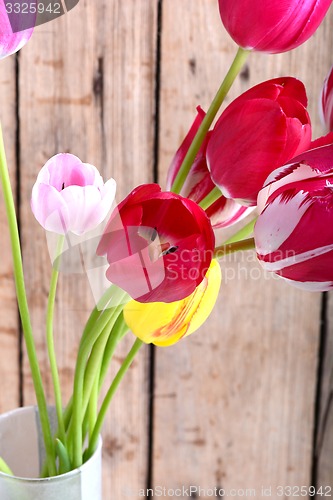 Image of Bouquet of red tulips against a wooden background, close up flowers