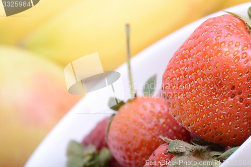 Image of Fruits. Arrangement of various fresh ripe fruits: bananas, apple and strawberries closeup