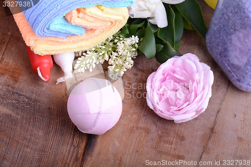 Image of towels, aroma oil, flower and sea salt on wooden plate 