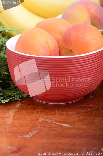 Image of bananas and apricots on red plate, close up