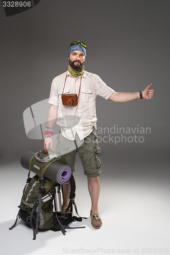 Image of Male tourist with backpack hitchhiking on gray background