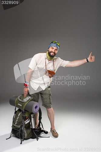 Image of Male tourist with backpack hitchhiking on gray background