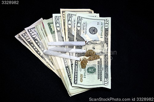 Image of fanned money with marijuana on black