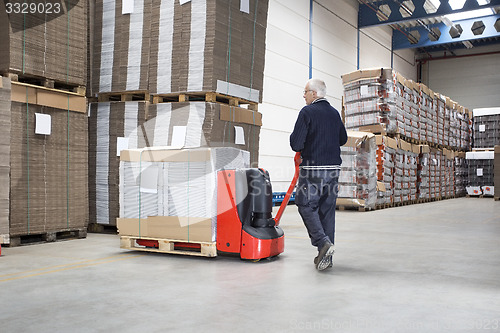 Image of Worker Pushing Handtruck Loaded With Goods