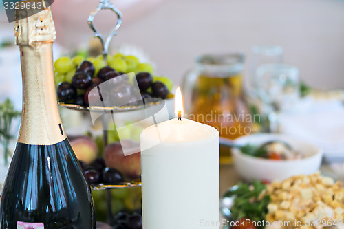 Image of Candle and champagne bottle on table