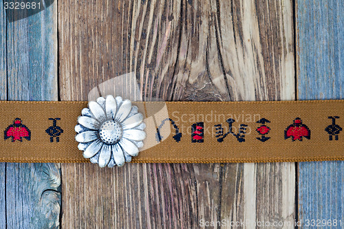 Image of vintage band with embroidered ornaments and old button flower