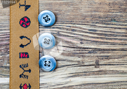 Image of vintage tape with embroidered ornaments and three old button