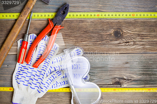 Image of vintage hammer, pliers, screwdriver, tape measure, gloves and sa