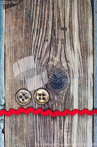 Image of still life with old red tape and two vintage buttons