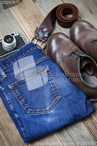 Image of brown boots, blue jeans, leather belt and rangefinder camera