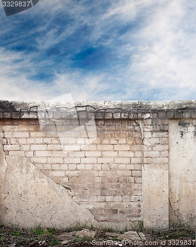 Image of Blue sky with clouds behind the cracked wall