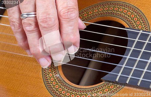 Image of Old woman\'s hand playing guitar
