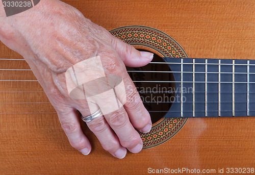 Image of Old woman\'s hand playing guitar