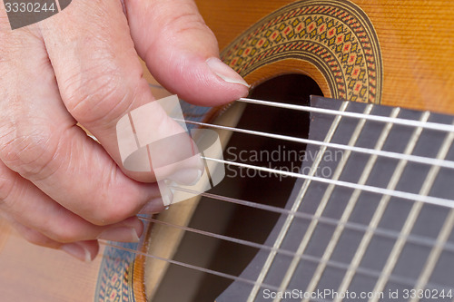 Image of Old woman\'s hand playing guitar