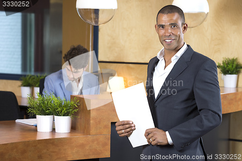 Image of Businessman Holding Documents At Reception Counter