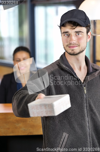 Image of Delivery Man Giving Package In Office