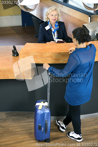 Image of Woman With Luggage At Hotel Reception