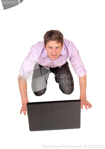 Image of Man kneeling in front of laptop.