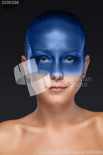 Image of Portrait of a woman who is posing covered with blue paint