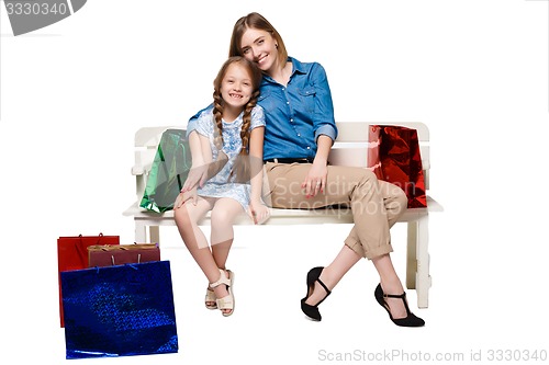 Image of Happy a mother and daughter with shopping bags sitting at studio 