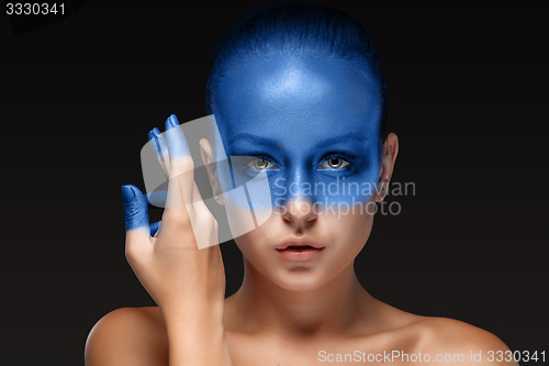 Image of Portrait of a woman who is posing covered with blue paint