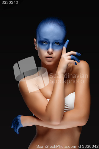 Image of Portrait of a woman who is posing covered with blue paint