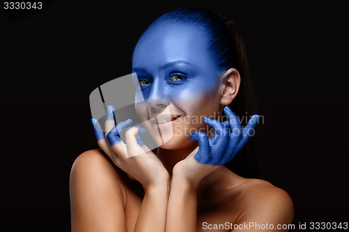 Image of Portrait of a woman who is posing covered with blue paint