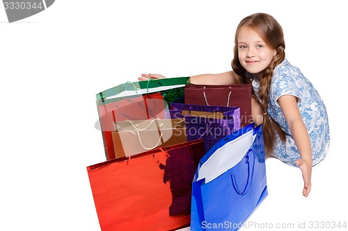 Image of Happy girl with shopping bags sitting at studio 