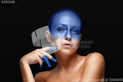 Image of Portrait of a woman who is posing covered with blue paint