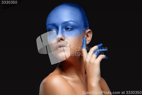 Image of Portrait of a woman who is posing covered with blue paint