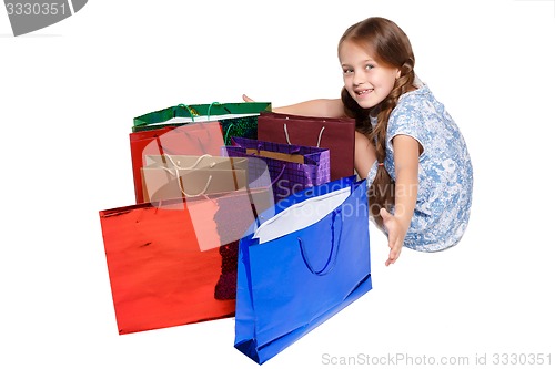 Image of Happy girl with shopping bags sitting at studio 