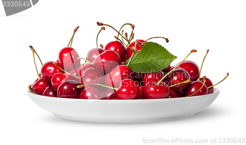 Image of Pile of sweet cherries with leaf on white plate