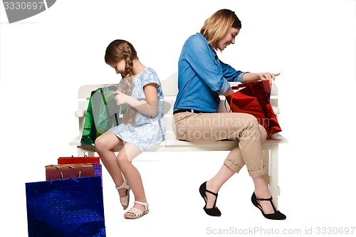 Image of Happy  mother and daughter with shopping bags sitting at studio 