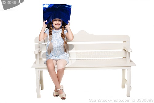 Image of Happy girl with shopping bags sitting at studio 